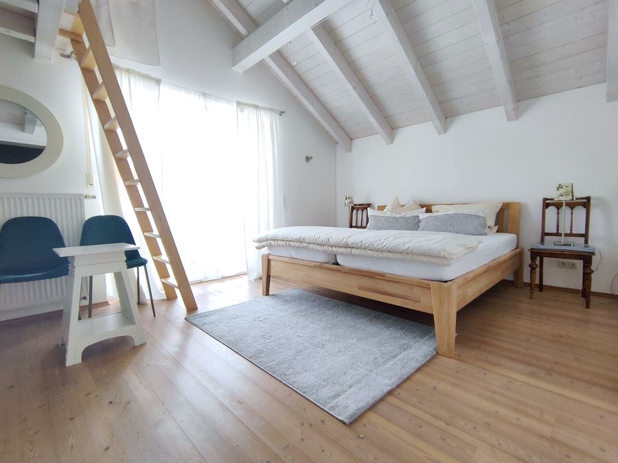 Großes Schlafzimmer mit Doppelbett und Leiter zur Galerie