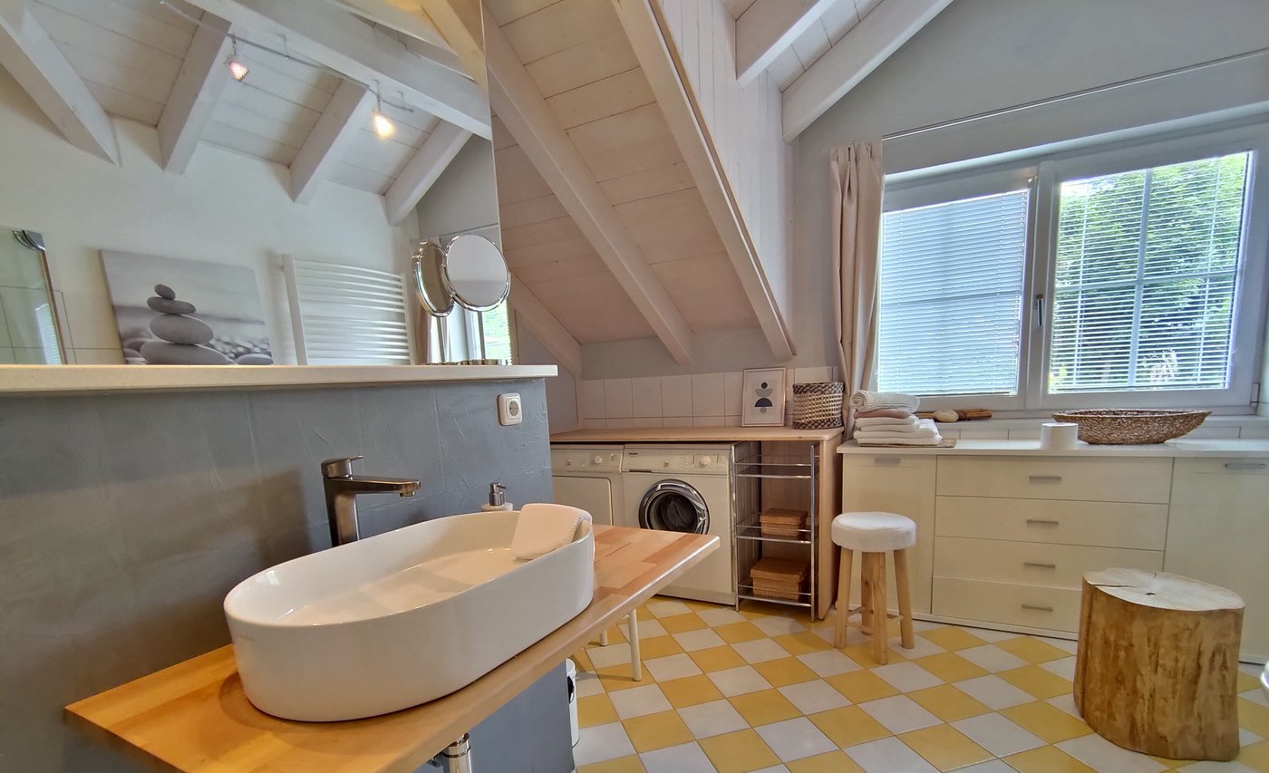 Waschtisch und Waschmaschine unter der Dachschräge im optional zubuchbaren zweiten Badezimmer der Ferienwohnung Panorama